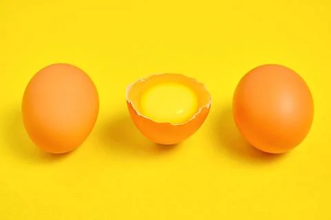 Chicken eggs on a yellow background broken with yolk. Stock Photos
