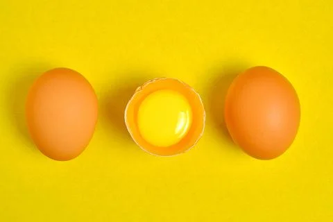 Chicken eggs on a yellow background broken with yolk. Stock Photos