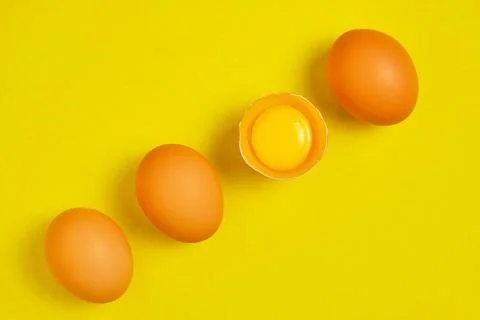 Chicken eggs on a yellow background broken with yolk. Stock Photos