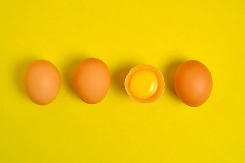 Chicken eggs on a yellow background broken with yolk. Stock Photos
