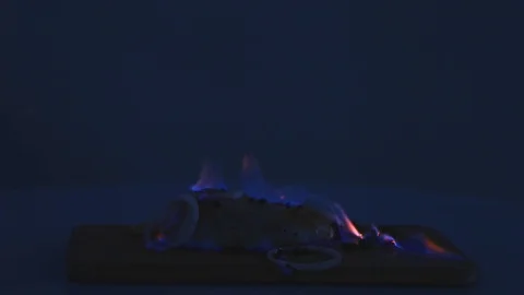 Chicken fillet in the fire on the wooden board. Barbecue meat. Dark background Stock Footage