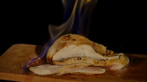 Chicken fillet in the fire on the wooden board. Barbecue meat. Dark background Stock Footage