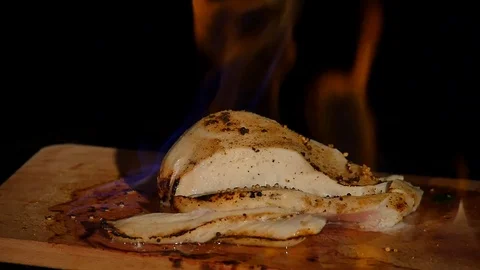 Chicken fillet in the fire on the wooden board. Barbecue meat. Dark background Stock Footage