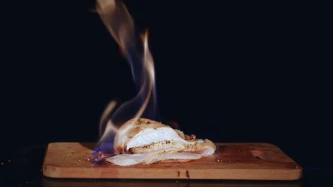 Chicken fillet in the fire on the wooden board. Barbecue meat. Dark background Stock Footage