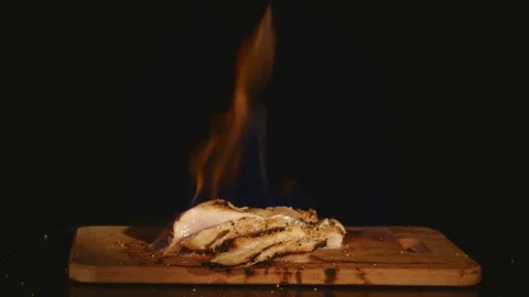 Chicken fillet in the fire on the wooden board. Barbecue meat. Dark background Stock Footage