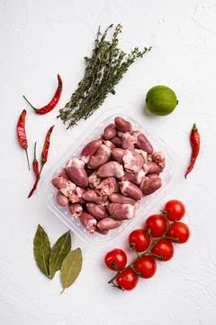 Chicken hearts in plastic tray, on white stone table background, top view fla Stock Photos