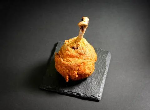 Chicken leg in breaded, on a dark basalt stand Stock Photos