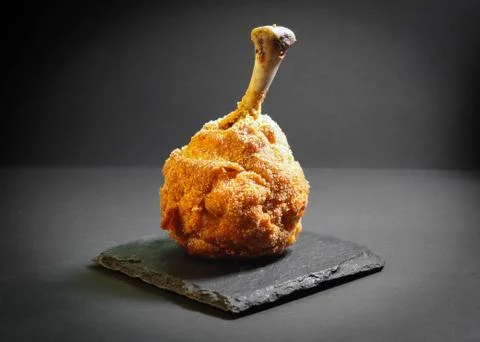 Chicken leg in breaded, on a dark basalt stand Stock Photos