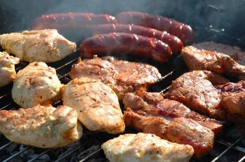 Chicken meat, pork meat and sausages cooking on a barbecue. Stock Photos