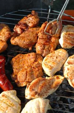 Chicken meat, pork meat and sausages cooking on a barbecue. Stock Photos