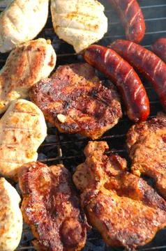 Chicken meat, pork meat and sausages cooking on a barbecue. Stock Photos