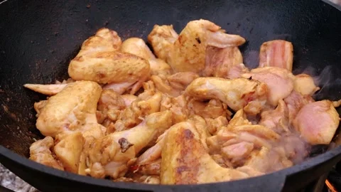 Chicken meat is stewed in a cauldron. A dish on a fire in a cauldron. The meat Stock Footage 280928970