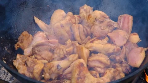 Chicken meat is stewed in a cauldron. A dish on a fire in a cauldron. The meat Stock Footage 282829611