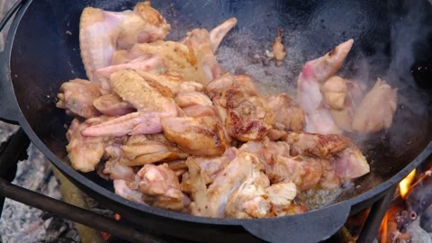 Chicken meat is stewed in a cauldron. A dish on a fire in a cauldron. The meat Stock Footage 282829988