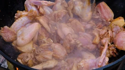 Chicken meat is stewed in a cauldron. A dish on a fire in a cauldron. The meat Stock Footage 307313869