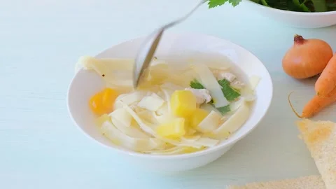 Chicken noodle soup video.  Hand holding a spoon scooping soup Stock Footage 279972453