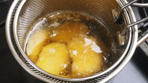 Chicken nuggets in a deep-fat grid are fried in boiling oil. Medium shot. Stock Footage 308879689