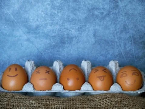 Chicken or Easter eggs with funny faces on black background. Stock Photos