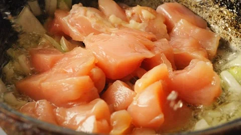 Chicken pieces fall into a pan with fried onions in boiling oil Stock Footage 243128184