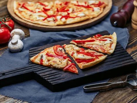 Chicken pizza slice tomato slice, red bell pepper, mushroom, cheese on wood Stock Photos