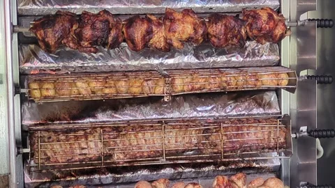 Chicken potatoes and ribs on a rotating spit oven Stock Footage 306242594