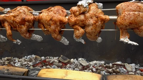 Chicken roasted on spit being grilled over the bright glowing coals Stock Footage 108767772