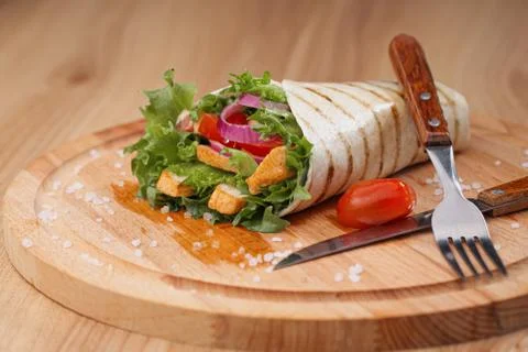 Chicken roll, cooked on fire in a thin dough tortilla with vegetables and salad Stock Photos