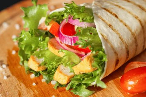 Chicken roll, cooked on fire in a thin dough tortilla with vegetables and salad Stock Photos