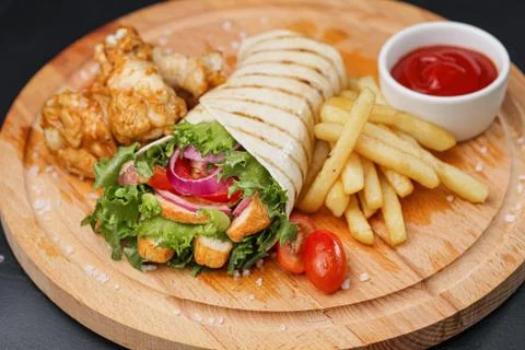 Chicken roll, cooked on fire in a thin dough tortilla with vegetables and salad Stock Photos