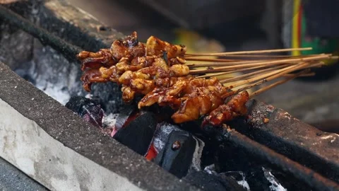 Chicken satay is grilled over an open fire with hot coals and smoke coming out. Stock-Footage 317445287