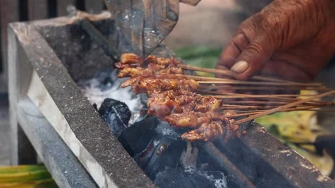 Chicken satay is grilled over an open fire with hot coals and smoke coming out. Stock-Footage 317445902