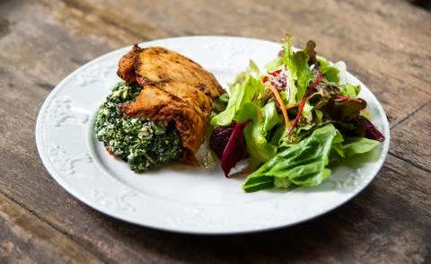 Chicken Spinach with salad on table Stock Photos