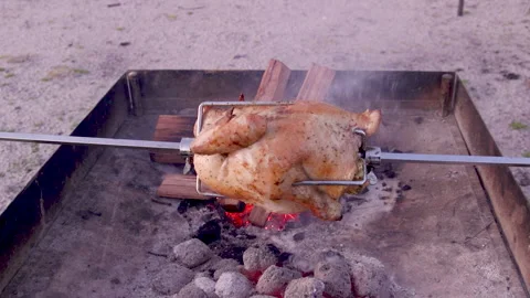Chicken spinning on a spit over an open fire with smoke and heat rising Stock Footage 327606782