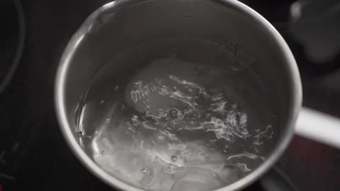 Chicken white big eggs are boiled in boiling water in ametal old pan on stove in Video stock 316913301
