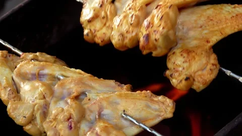 Chicken wings rotated on the grill grid above the open fire outdoors Stock Footage 311059761