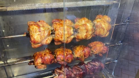 Chickens roasting on a rotating grill, four in a row, visible through the ove Stock Footage 301865142