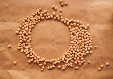 Chickpea beans lie in the shape of a circle on a brown paper background. Place Stock Photos