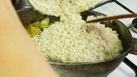 Chief adding rice in kettle with simmering ingredients of pilaf Stock Footage 32597877