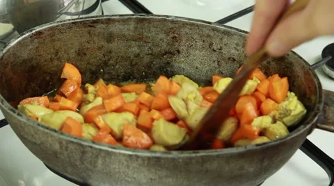 Chief adding sliced carrot and mixing with meat in simmering oil Stockbeeldmateriaal 32596730