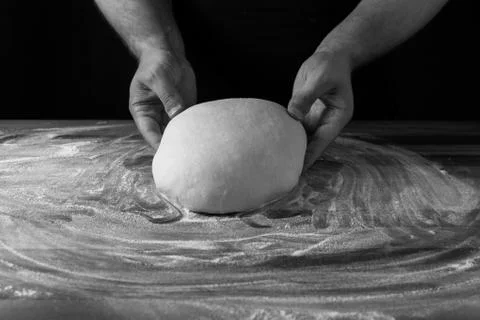 Chief baker preparing dough for bread in a bakery. Kitchen professional. Black Stock Photos