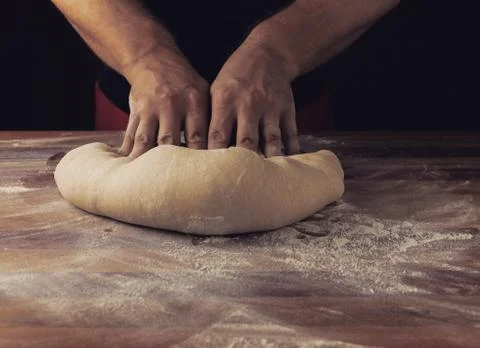 Chief baker preparing dough for bread in a bakery. Kitchen professional. Stock Photos