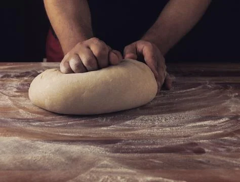 Chief baker preparing dough for bread in a bakery. Kitchen professional. Stock Photos
