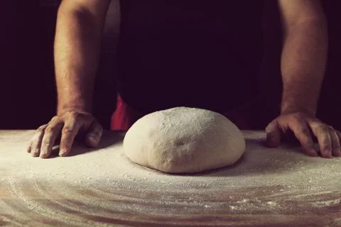 Chief baker preparing dough for bread in a bakery. Kitchen professional. Stock Photos