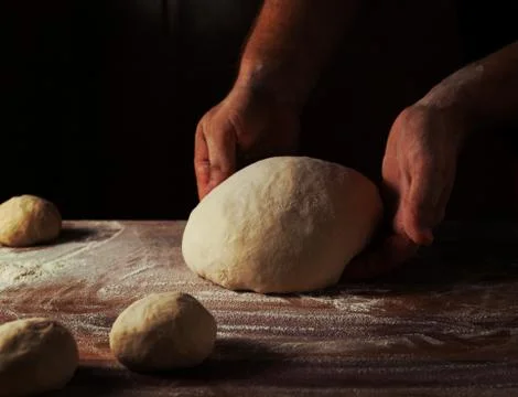 Chief baker preparing dough for bread in a bakery. Kitchen professional. Stock Photos