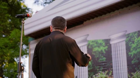 Chief conductor directing symphony orchestra with performers outdoor at sunset. Stock Footage 110595136