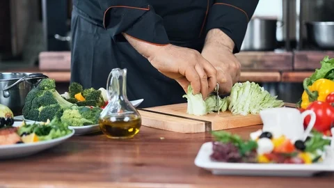 Chief cook arm cutting raw lettuce leaf. Medium close up shot on 4k RED camera Stock Footage 124157803