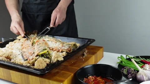 Chief cook is breaking salt and carving fish baked in salt crust. Stock Footage 147940950
