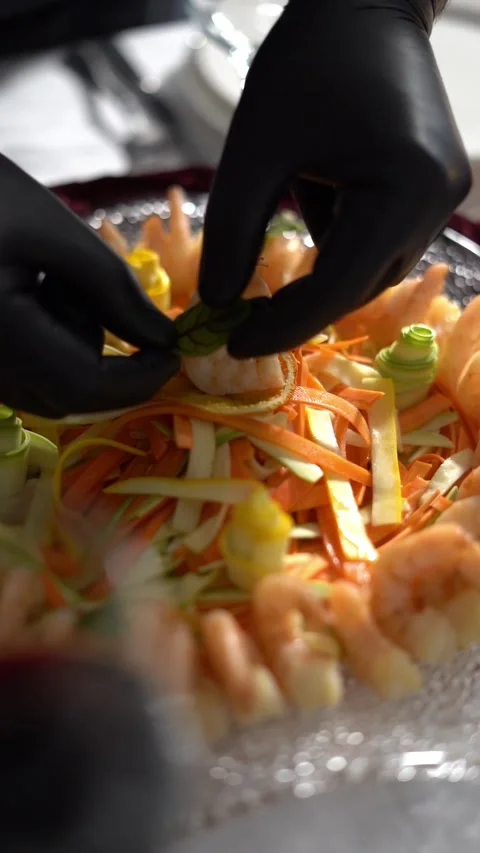 A chief decorates a plated shrimp dish with colorful peppers, garnished with a 動画素材 333718041