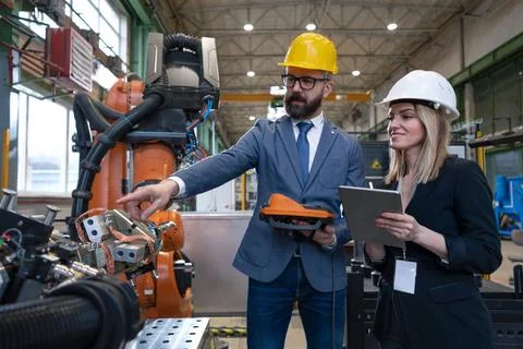 Chief engineer and project manager in modern industrial factory with robot... Stock Photos