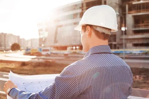 Chief Engineer with a drawing in hand looking at the construction site. View Stock Photos